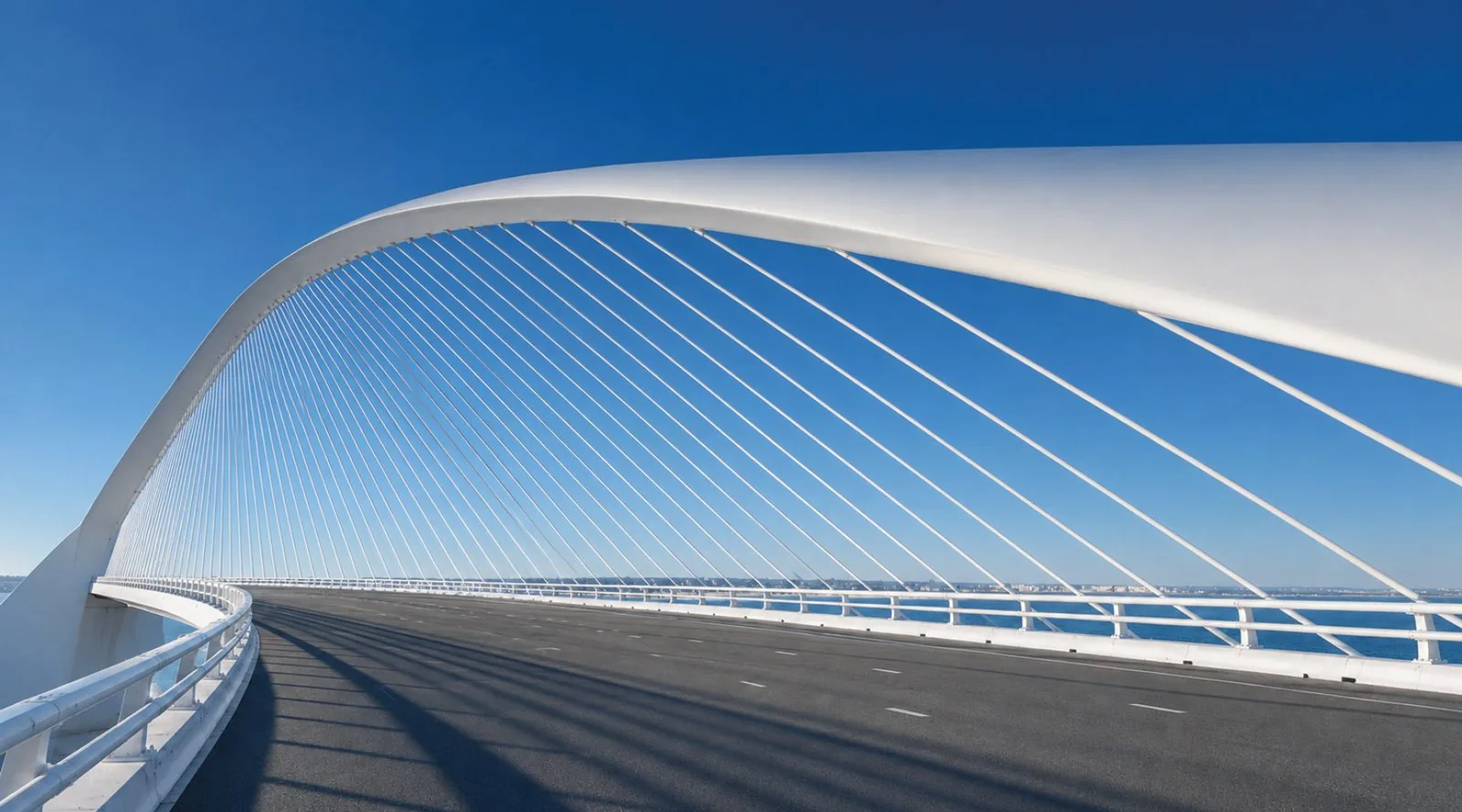 Modern cable-stayed bridge sweeping across open water under a clear sky
