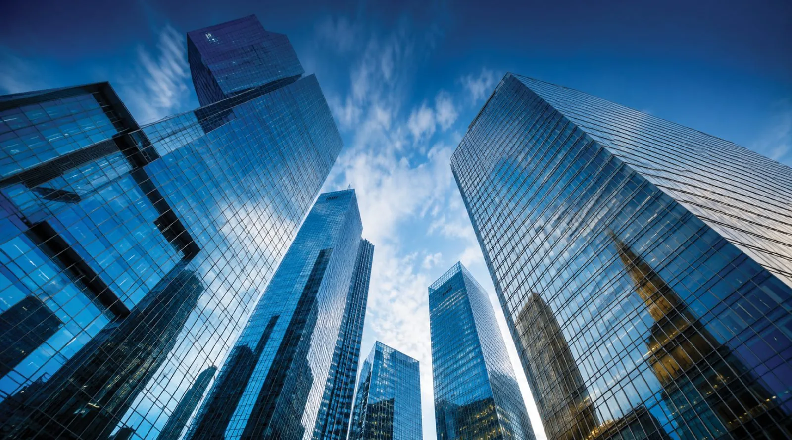 Glass skyscrapers seen from below against a blue sky