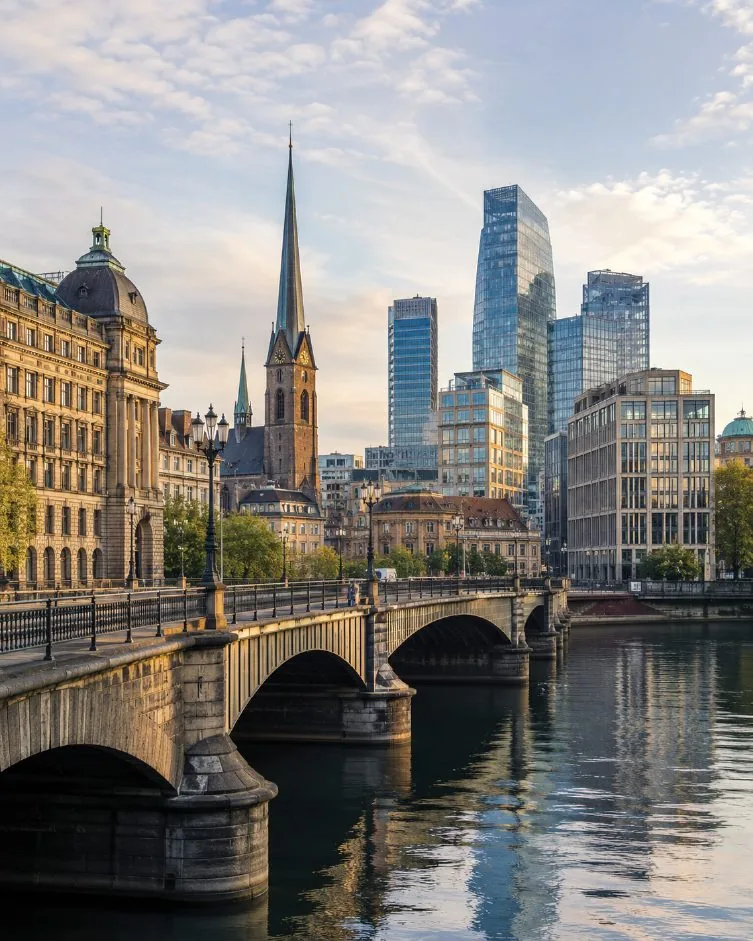 Historic stone bridge and church spires in front of a modern city skyline